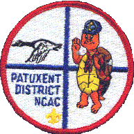 Patuxent District NCAC Logo. Red circle surrounding a blue cross with a flying goose in the upper left corner, a tortoise as a Webelo on the right side, and PATUXENT DISTRICT NCAC in blue followed by a gold fleur d le